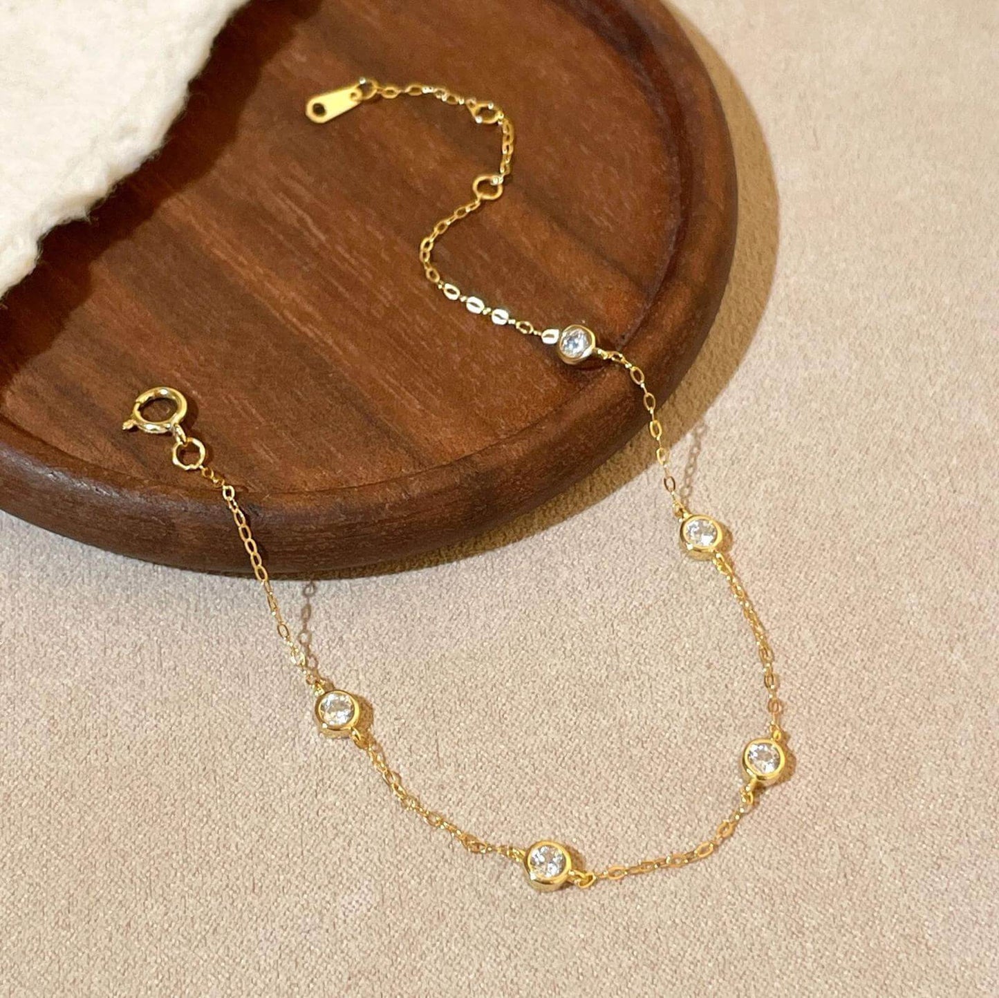 KorLuxé Gold-Plated Crystal Station Bracelet displayed on a wooden plate showcasing its elegant design and sparkling crystals.